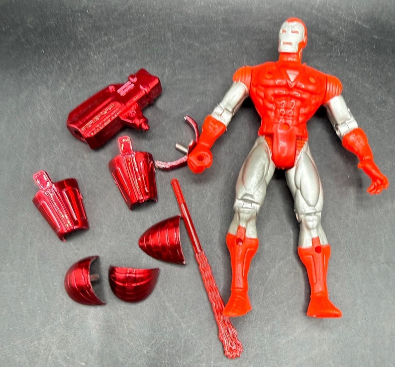 Puede incluir: Una figura de acci&oacute;n de Iron Man roja y plateada con piezas desmontables. La figura tiene un torso, brazos y piernas rojos, con piernas y brazos plateados. Varios accesorios rojos est&aacute;n esparcidos alrededor de la figura.