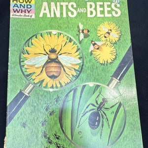 Puede incluir: Un libro infantil vintage titulado "The How and Why Wonder Book of Ants and Bees". La portada presenta una lupa que revela una abeja en una flor amarilla y una hormiga en una hoja verde.