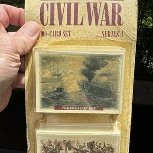 May include: A vintage card set featuring illustrations of famous battles of the American Civil War. The set includes 100 cards and is labeled "Series 1". The front of the package shows two cards, one depicting the Peninsula Campaign and the other depicting the Seven Days Battles.