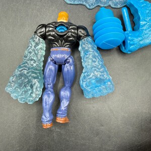 May include: A blue and black action figure with translucent blue arms and a yellow head. The figure is wearing blue pants and brown boots. Additional blue accessories are included, such as a cloud and a water blast.