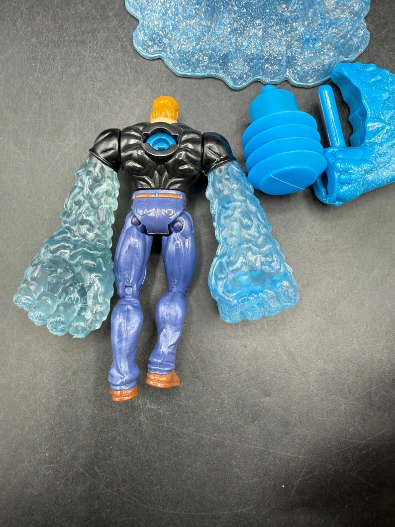 May include: A blue and black action figure with translucent blue arms and a yellow head. The figure is wearing blue pants and brown boots. Additional blue accessories are included, such as a cloud and a water blast.