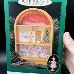 Puede incluir: Una caja verde con un adorno de madera en su interior. El adorno es un escenario en miniatura para el ballet El Cascanueces. La caja dice "Keepsake Ornament" y "The Nutcracker Ballet New Collector's Series".