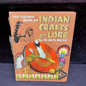May include: A vintage book titled "The Golden Book of Indian Crafts and Lore" by W. Ben Hunt. The cover features an illustration of a Native American chief and various Native American crafts in a colorful design. The book is in a rectangular shape.