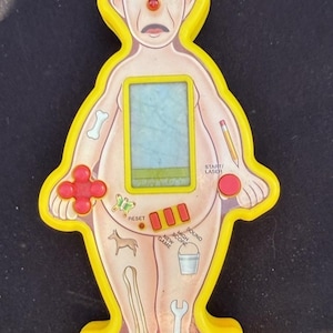 May include: A vintage Operation game in a yellow plastic frame shaped like a patient. The game features a screen, buttons, and illustrations of body parts. The word "OPERATION" is printed at the bottom.