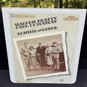 Op de afbeelding: Een vintage RCA Videodisc-hoes voor de film "Bonnie and Clyde" met Warren Beatty en Faye Dunaway. De hoes bevat een sepiafoto van de cast en het Warner Home Video-logo.