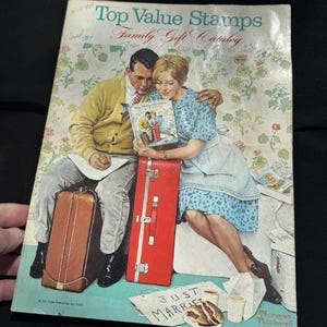 Puede incluir: Una portada vintage del catálogo de regalos familiares Top Value Stamps que muestra a una pareja con equipaje y un cartel de "Just Married". La pareja está mirando un libro titulado "Top Value Stamps". La imagen está ilustrada en un estilo vintage por Norman Rockwell.