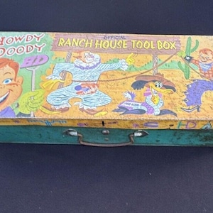 May include: Vintage metal toolbox with a colorful illustration of cartoon characters. The text on the box reads "Howdy Doody" and "Official Ranch House Toolbox".