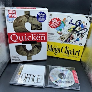 May include: A collection of vintage software boxes and CD-ROMs. The boxes include "Quicken" for Windows, "Key Mega ClipArt" for Windows, and two Microsoft Office and Windows 95 CD-ROMs. The "Quicken" box features a dollar sign design.