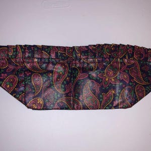 Peut inclure: Un tissu bleu foncé avec un motif paisley dans des tons de rose, vert et jaune. Le tissu a un bord festonné.