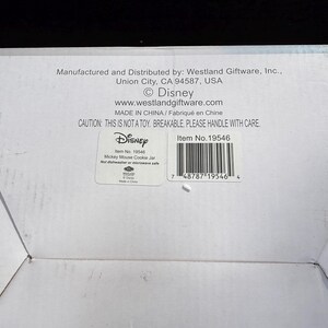 May include: White cardboard box with text including "Disney" and "Mickey Mouse Cookie Jar." The box also has a barcode and the text "CAUTION: THIS IS NOT A TOY. BREAKABLE. PLEASE HANDLE WITH CARE."