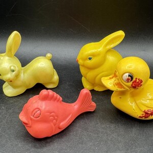 May include: A set of four vintage rubber bath toys. The toys are a yellow rabbit, a yellow duck, a yellow bunny, and a red fish. The toys are all in good condition and have a retro look.