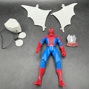 May include: A Spider-Man action figure in a classic red and blue suit, with web-wing accessories and a web-shooter. The figure is posed upright, with additional accessories including a chest emblem and a web-slinging device.
