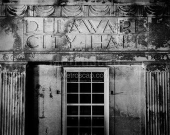 May include: Black and white photo of a building with the words "DELAWARE CITY HALL" etched into the stone above a window.