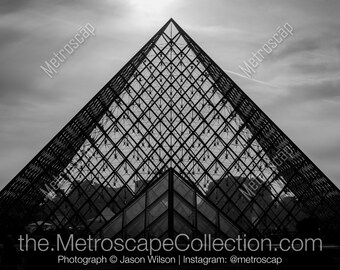 May include: A black and white photograph of the Louvre Pyramid in Paris, France. The pyramid is made of glass and metal and is a popular tourist destination.