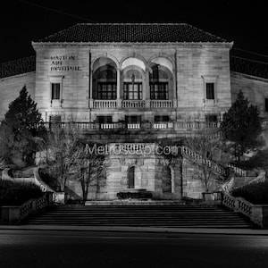 Może przedstawiać: Czarno-białe zdjęcie Dayton Art Institute w nocy. Budynek ma duże schody prowadzące do wejścia. Po obu stronach schodów znajdują się dwie latarnie.