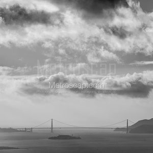 May include: A black and white photograph of the Golden Gate Bridge in San Francisco, California. The bridge is silhouetted against a cloudy sky.