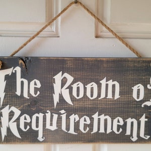 以下が含まれることがあります： 「The Room of Requirement」という文字が白く書かれた、素朴な木製の看板。ロープで吊り下げられており、古びて風化したような外観です。
