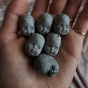 Pequeñas y espeluznantes decoraciones de cemento con cabezas de bebé para plantas en macetas o jardines de hadas