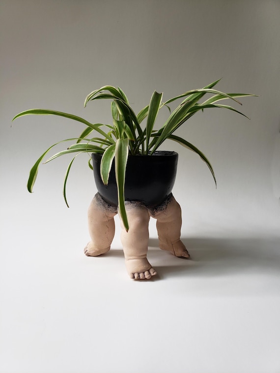 Cement planters with cast baby doll legs sticking out — genuinely unsettling, funny, and conversation-starting; 140 favorites backs it up.