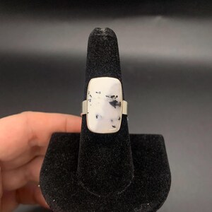 May include: A silver ring with a white and black stone set in a rectangular shape.