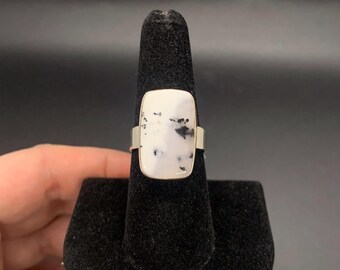 May include: A silver ring with a white and black stone set in a rectangular shape.