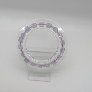 May include: A purple beaded bracelet on a clear display stand.