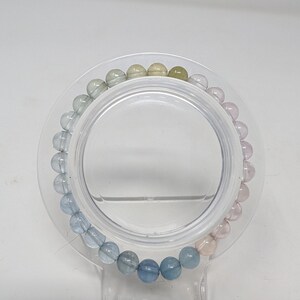 May include: A bracelet made of round, light blue, pink, and green gemstone beads.