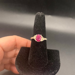 May include: A silver ring with a pink oval gemstone set in a Celtic knot design.