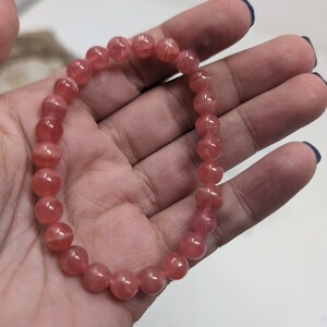 May include: A pink gemstone bracelet with round beads. The bracelet is made of natural stones and is a beautiful accessory for any occasion.