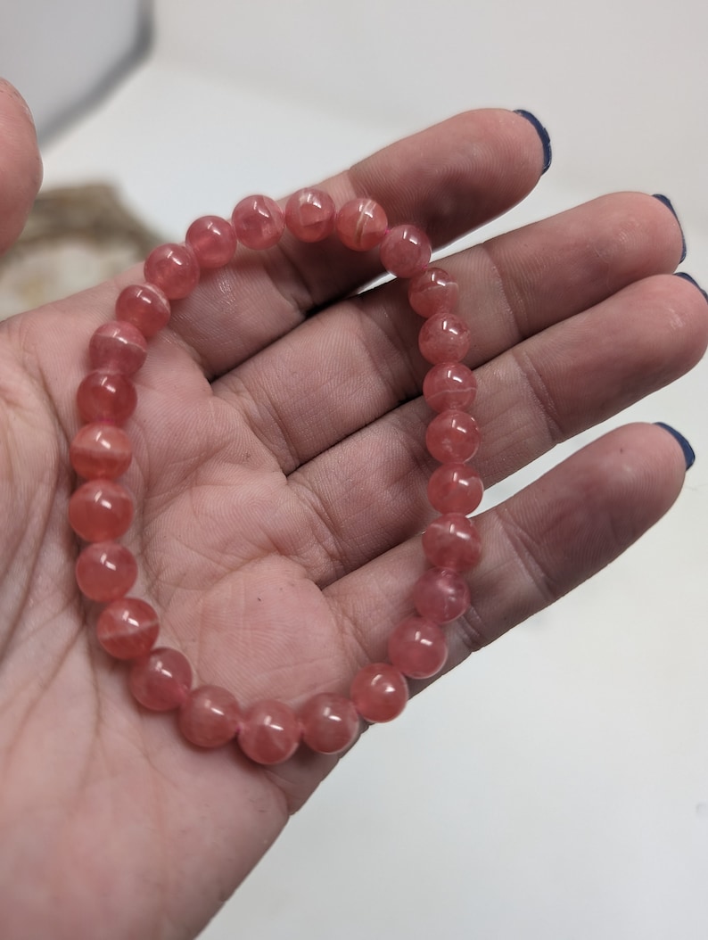 May include: A pink gemstone bracelet with round beads. The bracelet is made of natural stones and is a beautiful accessory for any occasion.
