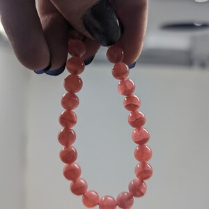 May include: A pink gemstone bracelet with round beads.