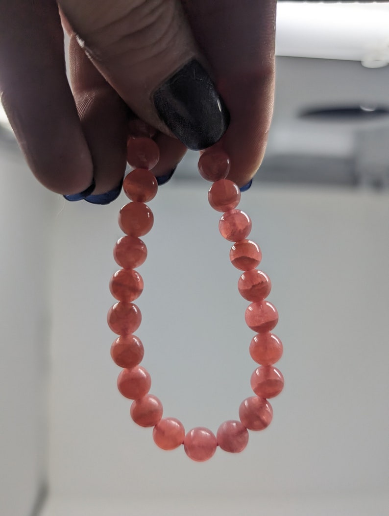 May include: A pink gemstone bracelet with round beads.