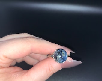 May include: A silver ring with a blue and white gemstone. The gemstone has a swirling pattern.