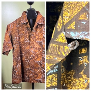 May include: A brown and yellow patterned short-sleeved shirt with a button-up front. The shirt has a geometric pattern with a light blue accent.