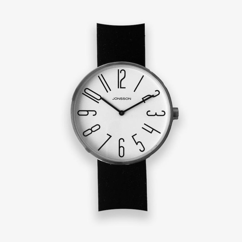 May include: A black leather wristwatch with a white face and black numbers. The watch face has the text "JONSSON" printed on it.