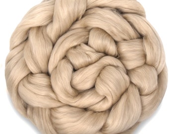 May include: A close-up of a large amount of beige wool roving. The wool is soft and fluffy, and it is perfect for spinning or felting.
