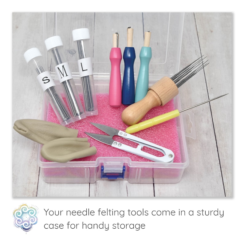 May include: A clear plastic case containing needle felting tools. The kit includes needles in labeled tubes, pink, blue, and wooden handled tools, scissors, and clay pieces. The case sits on a light wood surface.
