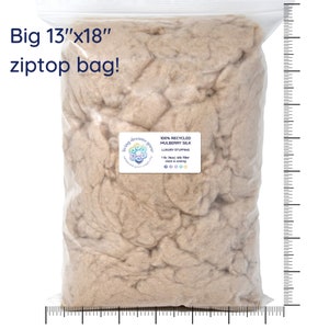 May include: A large, clear plastic bag filled with a beige, fluffy material. The bag is labeled "100% Recycled Mulberry Silk Luxury Stuffing 1 lb (Max) silk filler clean & cooling" and has a logo that says "living dreams green". The bag is 13 inches by 18 inches.