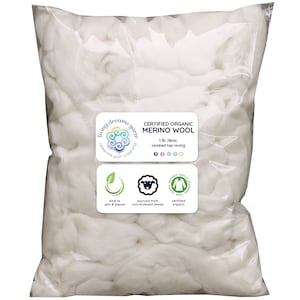 May include: A white plastic bag filled with white, fluffy, certified organic merino wool roving. The bag has a label that reads "Living Dreams Yarn" and "Certified Organic Merino Wool 1 lb (16oz) combed top roving".