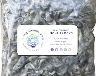 Puede incluir: Una bolsa de mechones de mohair gris claro, teñidos a mano y etiquetados con "REAL ORGANIC MOHAIR LOCKS 100% natural teñido a mano de la granja a ti" con un logotipo que dice "living dreams yarn celebrate your creativity".