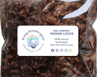 May include: A clear plastic bag filled with brown mohair locks. The bag has a label that reads "Living Dreams Yarn" and "Real Organic Mohair Locks". The label also states that the mohair is 100% natural, hand dyed, and from the farm to you.