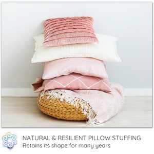 Peut inclure: Une pile de quatre coussins roses et blancs avec des d&eacute;tails en franges, pos&eacute;s sur un panier tiss&eacute; avec une couverture rose et blanche. Garnissage de coussin naturel et r&eacute;sistant. Conserve sa forme pendant de nombreuses ann&eacute;es.
