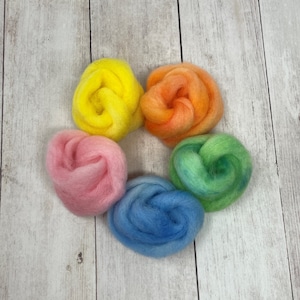 May include: Five balls of wool yarn in a rainbow color gradient. The colors are yellow, orange, pink, blue, and green.