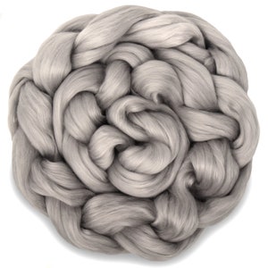 May include: A close-up of a large amount of grey wool roving. The wool is soft and fluffy, and it is perfect for spinning or felting.