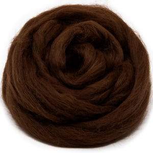 May include: A tightly coiled ball of dark brown wool roving. The fibers are densely packed, creating a textured, organic appearance. This material is suitable for various fiber art projects, including needle felting and wet felting.