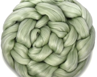 May include: A close-up of a bundle of soft, light green silk fiber. The fiber is twisted and knotted together, creating a textured and fluffy appearance.