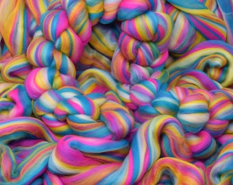 Puede incluir: Primer plano de un montón de lana roving arcoíris. La lana es suave y esponjosa, y los colores son vibrantes y brillantes.