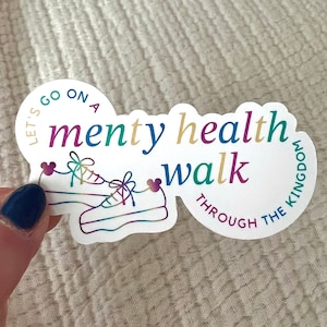 以下が含まれることがあります： 「Let's go on a menty health walk through the kingdom」というテキストが書かれたカラフルなステッカー。ステッカーには、靴ひもにハートが付いたスニーカーのペアが描かれています。