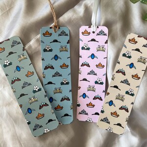 May include: Four colorful bookmarks with a crown and floral design. The bookmarks are made of paper and have a white background with blue, pink, and cream accents. The bookmarks are all different designs but have the same theme.