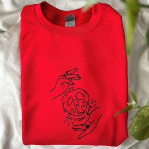 May include: Red sweatshirt featuring a black graphic of a hand holding a poisoned apple with the text "Just One Bite".